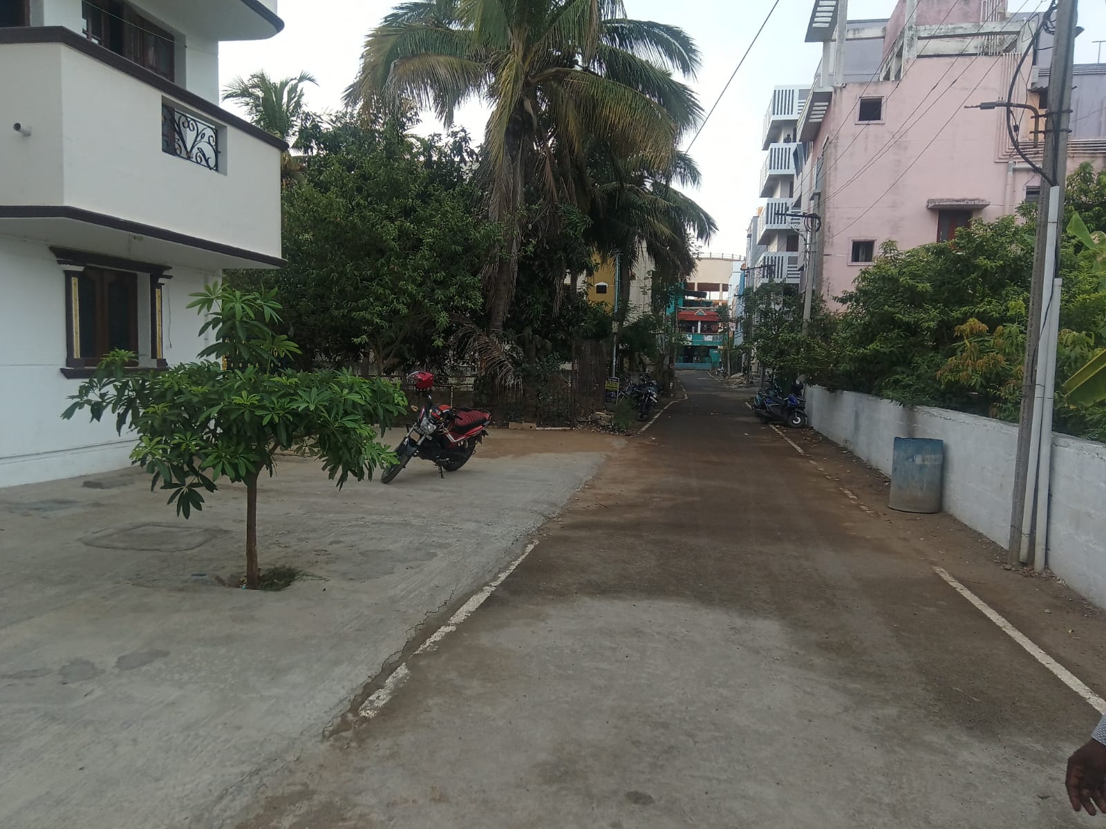 A quiet residential lane near the Sriperumbudur belt, with houses, coconut palms and parked motorbikes along a concrete street