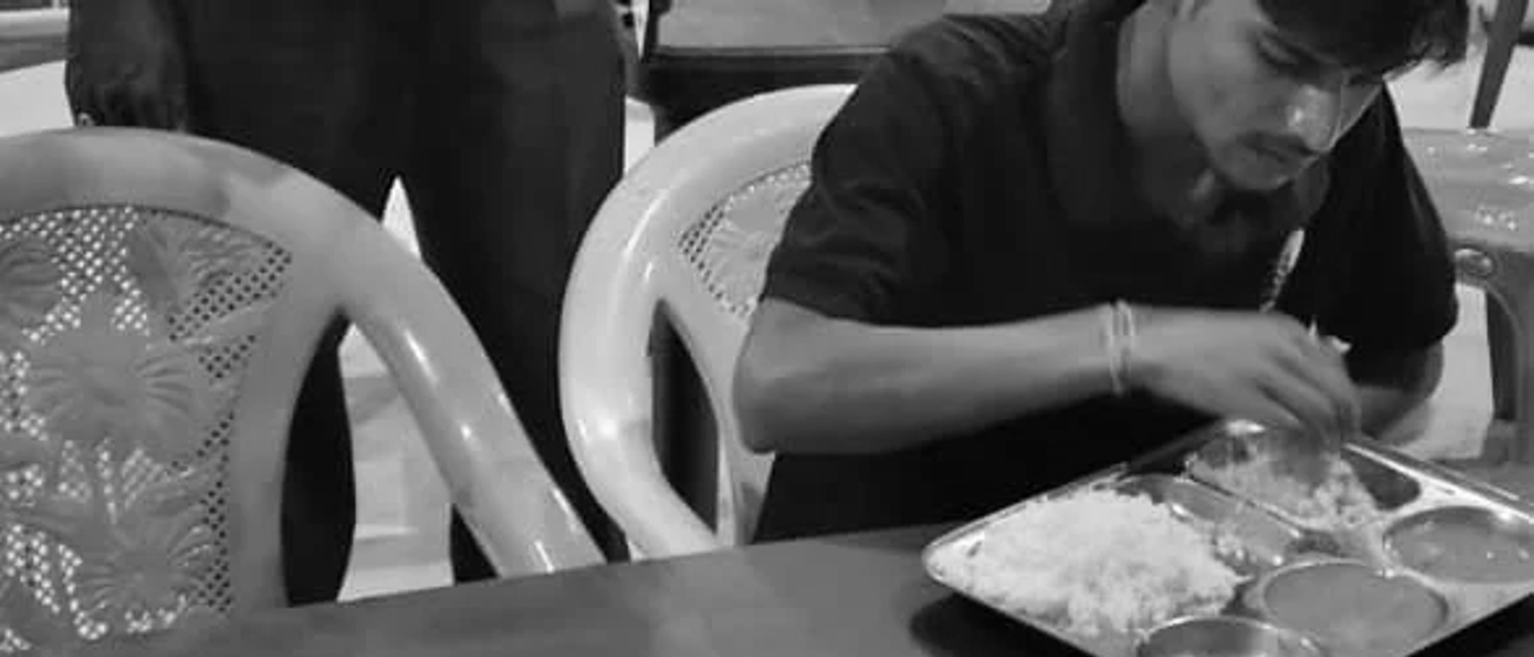 A member eating a home-style thali meal in the common dining area of a Nia Studio near a manufacturing plant
