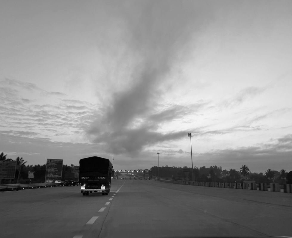 A truck on a national highway heading toward a toll plaza at dawn